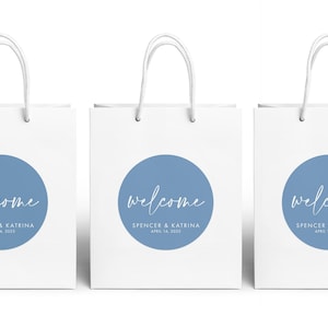 Three white paper bags with blue circular designs and the text "Welcome Spencer & Katrina April 14, 2020" printed on them.