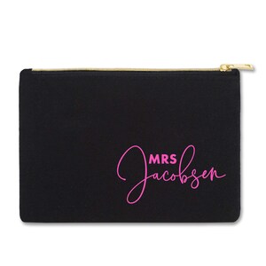 May include: Black canvas zippered pouch with a pink cursive inscription that reads "MRS Jacobsen".