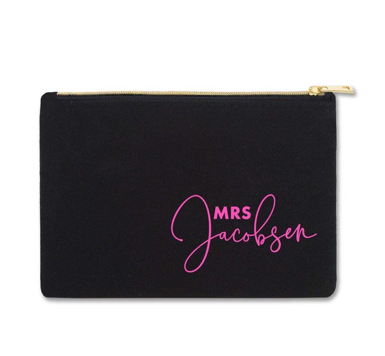 May include: Black canvas zippered pouch with a pink cursive inscription that reads "MRS Jacobsen".