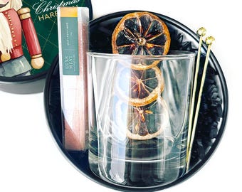 May include: A festive cocktail kit with a clear glass, dried orange slices, and gold-colored stir sticks. The kit includes a container with the text "Merry Christmas" and a box labeled "Luxe Mint Old Fashioned".