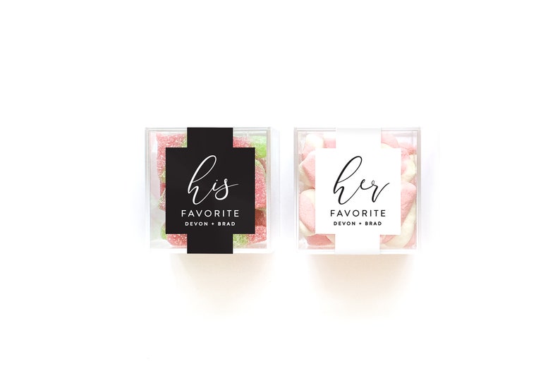 May include: Two clear plastic boxes filled with candy. One box has a black label that says "his favorite Devon + Brad". The other box has a white label that says "her favorite Devon + Brad".