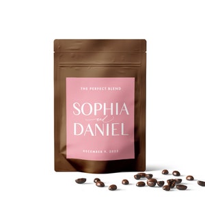 Puede incluir: Una bolsa de papel marr&oacute;n con una etiqueta rosa que dice "The Perfect Blend" y "Sophia and Daniel" con la fecha "December 9, 2023". Granos de caf&eacute; esparcidos sobre una superficie blanca.