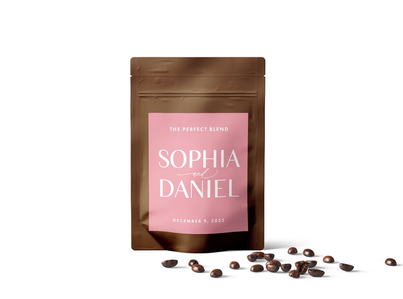 Puede incluir: Una bolsa de papel marr&oacute;n con una etiqueta rosa que dice "The Perfect Blend" y "Sophia and Daniel" con la fecha "December 9, 2023". Granos de caf&eacute; esparcidos sobre una superficie blanca.
