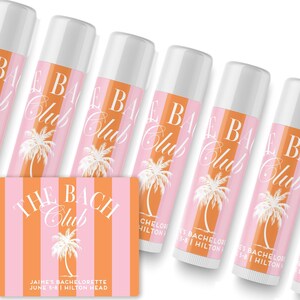 a collection of pink and white tubes of lip balm arranged in a row, with a pink and white striped card in the foreground.