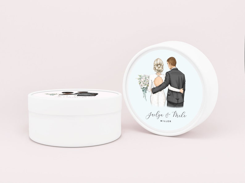 May include: White round box with a blue background and a watercolor illustration of a bride and groom. The text "Jaelya & Mike MILLER" is printed below the illustration.