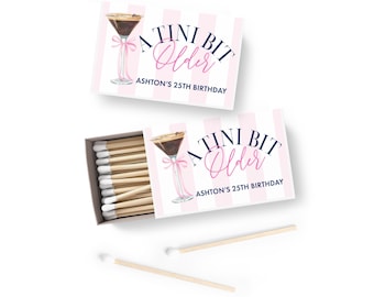 May include: Two matchboxes with a pink and white striped design. The text on the boxes reads "A Tini Bit Older" and "Ashton's 25th Birthday." One box is open, revealing white-tipped matches. A cocktail glass illustration with a pink bow is also featured.