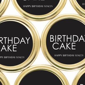 以下が含まれることがあります： ゴールドとブラックの丸いラベルに「Birthday Cake」と「Happy Birthday Stacey」の文字が書かれています。
