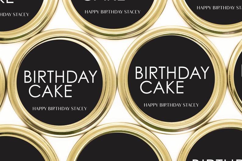以下が含まれることがあります： ゴールドとブラックの丸いラベルに「Birthday Cake」と「Happy Birthday Stacey」の文字が書かれています。