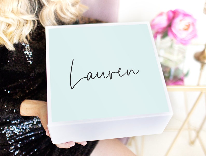 May include: A white gift box with a light blue lid. The lid has the name "Lauren" written in black cursive script.