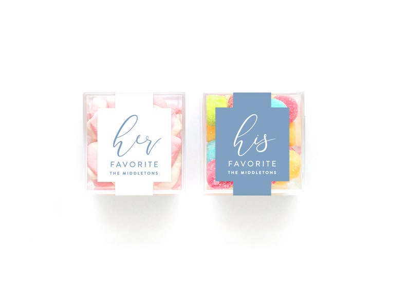 May include: Two clear acrylic boxes filled with colorful candies. One box has a white label with the text "her favorite the middleton's" and the other box has a blue label with the text "his favorite the middleton's".