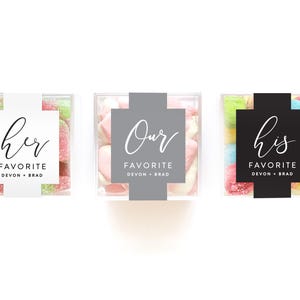 May include: Three square clear plastic boxes filled with colorful candies. Each box features a paper band with the text FAVORITE DEVON + BRAD. The left band is white with the word her, the center is gray with Our, and the right is black with his.