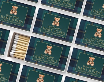 May include: A collection of rectangular matchboxes featuring a dark green and navy blue plaid pattern. Each box displays a watercolor illustration of a brown teddy bear and the text "welcome BABY JONES LAUREN'S BABY SHOWER" in gold lettering.