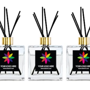 May include: Three square glass reed diffusers with gold-toned collars and black reeds. Each bottle features a black square label with a multi-colored flower graphic and the white text "YOUR LOGO HERE" followed by "WWW.WEBSITE.COM".