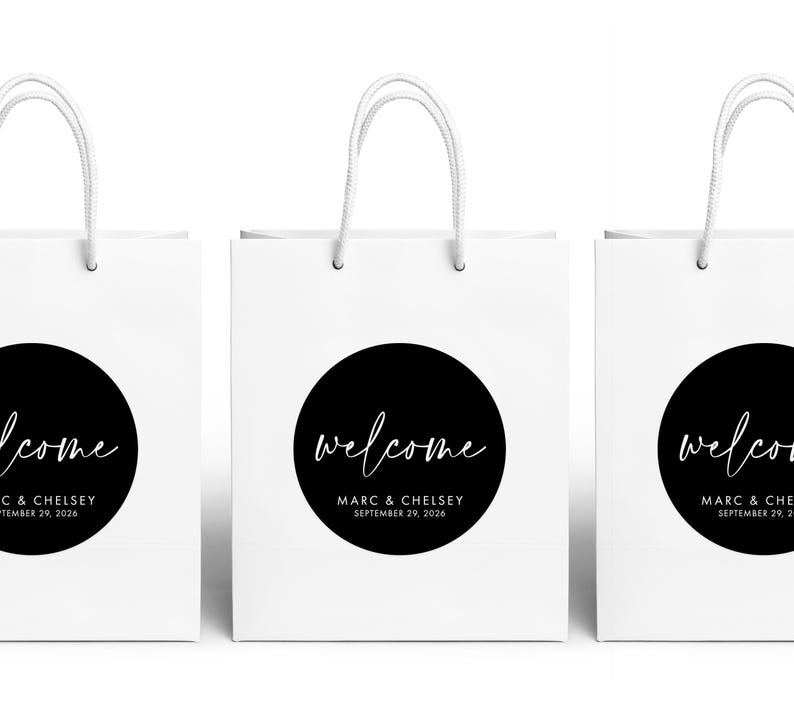 Three white paper bags with black text and logos, including a welcome message and the names Marc & Chelsea.