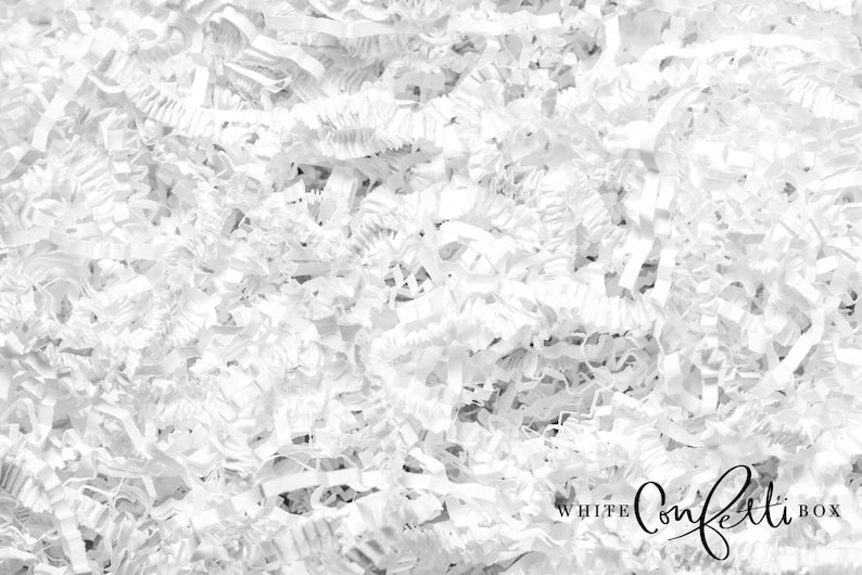 Puede incluir: Relleno de papel blanco triturado para cajas de regalo. El papel est&aacute; arrugado y texturizado, creando una apariencia suave y esponjosa. El texto "WHITE confetti BOX" es visible en la esquina inferior derecha de la imagen.