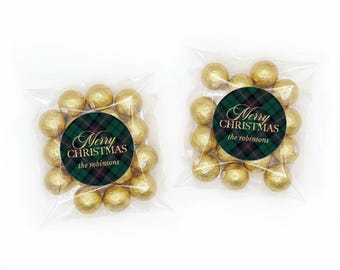 May include: Two clear plastic bags filled with gold foil-wrapped spherical chocolates. Each bag features a circular sticker with a green and navy blue plaid pattern, the text Merry CHRISTMAS, and the name the robinsons in gold lettering.