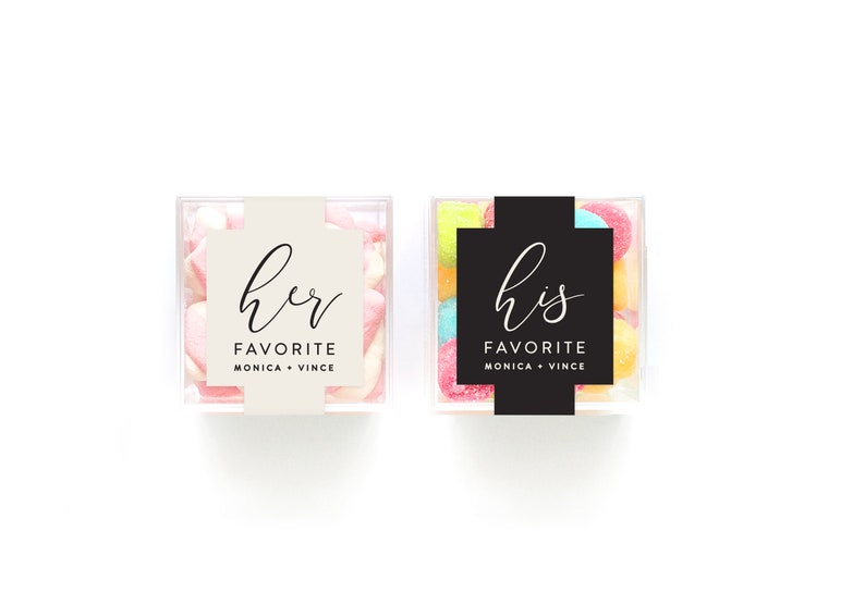 May include: Two clear square containers filled with colorful candies. One container has a white label with the text "her favorite Monica + Vince" and the other container has a black label with the text "his favorite Monica + Vince".