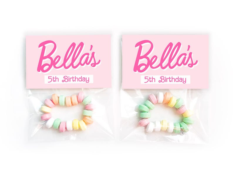 May include: Two clear plastic bags each containing a candy bracelet. Each bag has a pink card with the name "Bella's" in cursive and "5th Birthday" in a smaller font. The candy bracelets are made of pastel-colored candies.