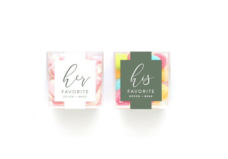 May include: Two clear plastic containers filled with colorful candies. One container has a white label that says "her favorite Devon + Brad". The other container has a green label that says "his favorite Devon + Brad".