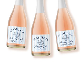 May include: Three glass bottles filled with a light pink liquid, each featuring a rectangular label with light blue vertical stripes. The label displays a blue seashell illustration and the text "SEASHELLS & Wedding Bells EMILIE'S BACHELORETTE JUNE 5-8 | NANTUCKET".