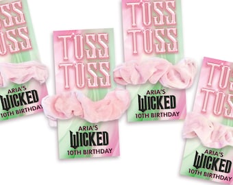 May include: Four light pink fabric hair scrunchies attached to rectangular display cards. Each card features the text TUSS TUSS in a stylized font at the top and ARIA'S WICKED 10TH BIRTHDAY in black lettering at the bottom over a pink and green background.