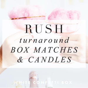 May include: Two clear stemmed glasses filled with pink cotton candy are held up in a toast. The text RUSH turnaround BOX MATCHES & CANDLES is centered in black font. At the bottom, the text WHITE CONFETTI BOX is printed in white.
