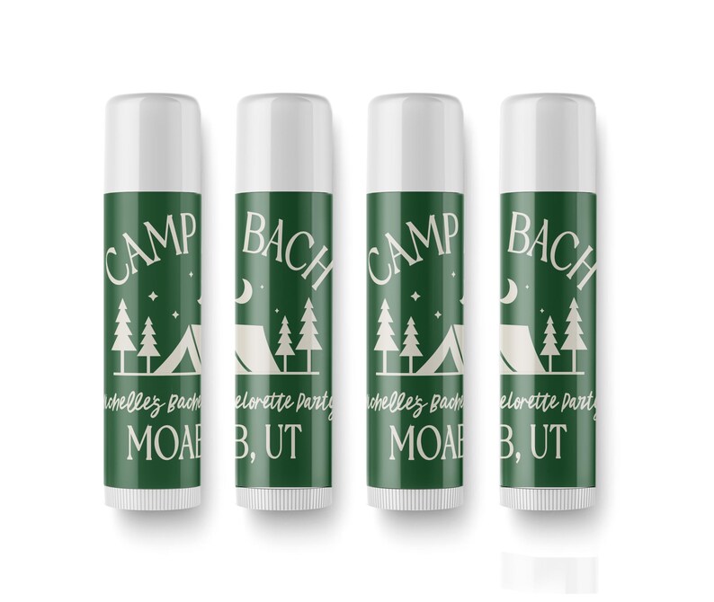 May include: Four green and white lip balm tubes with the text "CAMP BACH" and "MOAB, UT" printed on them. The tubes have a camping theme with a tent and pine trees.