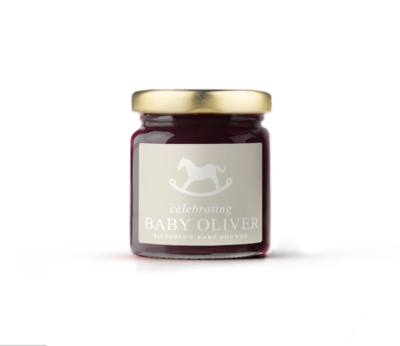 May include: A small glass jar with a gold lid filled with a dark red preserve. The jar has a label with a rocking horse illustration and the text "celebrating BABY OLIVER VICTORIA'S BABY SHOWER".