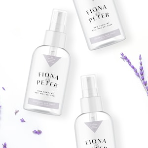 May include: Three clear glass spray bottles with white caps and labels that say "Fiona & Peter" in black text. The labels also include the text "New York, NY Est. May 08, 2025" and "Botanical Bug Spray 4 fl oz (118ml)". The bottles are on a white background with lavender flowers.