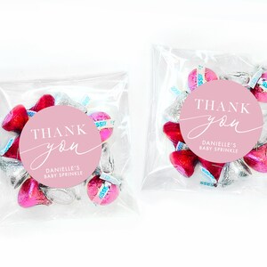 Peut inclure: Des sachets de faveur roses et argent&eacute;s remplis de baisers au chocolat et un autocollant rond rose avec du texte blanc qui dit "THANK you" et "DANIELLE'S BABY SPRINKLE".
