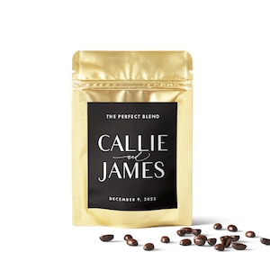 Puede incluir: Una bolsa de papel de aluminio dorado con una etiqueta negra que dice "The Perfect Blend" y "Callie and James" con la fecha "December 9, 2023". Granos de caf&eacute; esparcidos sobre una superficie blanca.