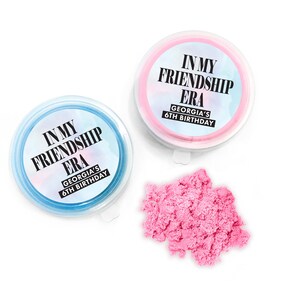 May include: Two small containers of pink and blue sand with a label that reads "In My Friendship Era Georgia's 6th Birthday".