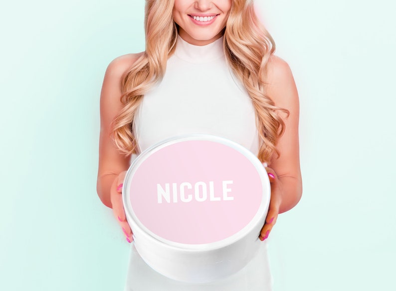 May include: A white round box with a pink lid. The lid has the name "NICOLE" printed in white letters.
