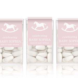 May include: Three pink and white favor boxes filled with white mints. Each box has a white rocking horse graphic and the text "celebrating Baby Sophia Maria's Baby Shower".