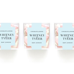May include: Three clear boxes filled with pink and white heart-shaped marshmallows. Each box has a blue label with the text "Congratulations Whitney & Tyler Baby Johnson".