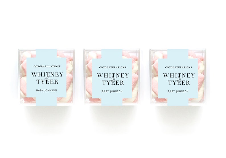 May include: Three clear boxes filled with pink and white heart-shaped marshmallows. Each box has a blue label with the text "Congratulations Whitney & Tyler Baby Johnson".