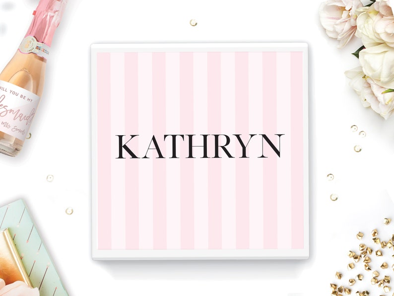 May include: A white box with pink and white stripes and the name "KATHRYN" printed in black.