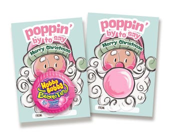 May include: Two light blue rectangular cards featuring a cartoon Santa Claus with a white beard and pink hat. The text reads poppin' by to say Merry Christmas. One card holds a round pink Hubba Bubba Bubble Tape container over the Santa's mouth.