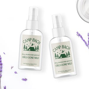 May include: Two clear plastic bottles with white spray tops and labels that say "Camp Bach Many Bachelorette Weekend Girls Gone Wild Botanical Bug Spray 2 fl oz (59ml)".