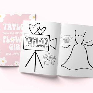 May include: A coloring book with a pink cover featuring white daisies and the text Taylor Thank You For Being Our Flower Girl Love-Kate. The open pages show a black and white line drawing of a movie camera with hearts and a wedding dress.