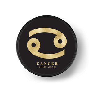 K&ouml;nnte beinhalten: Goldenes Krebs-Sternzeichen auf einem schwarzen Kreis mit dem Text "CANCER SHELBY | JULI 22".