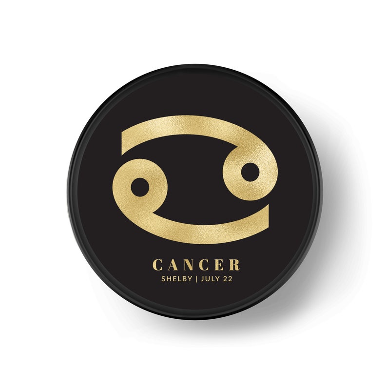 K&ouml;nnte beinhalten: Goldenes Krebs-Sternzeichen auf einem schwarzen Kreis mit dem Text "CANCER SHELBY | JULI 22".
