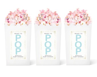 May include: Three white popcorn boxes with blue and gold labels. The labels say "Ready to Pop" with the word "Pop" in blue and the rest in gold. The labels also say "Jessica's Baby Shower".