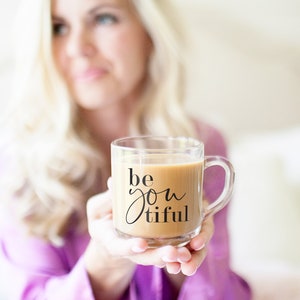 May include: A clear glass mug with a black handle filled with coffee and the text "be you tiful" printed on the side.