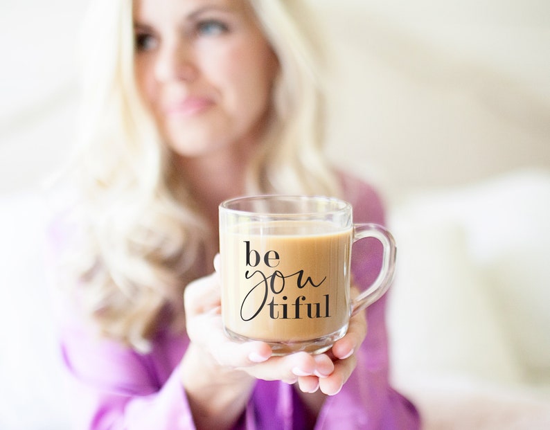 May include: A clear glass mug with a black handle filled with coffee and the text "be you tiful" printed on the side.