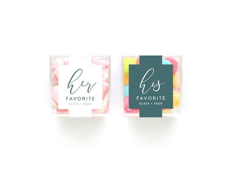 May include: Two clear plastic containers filled with colorful candies. One container has a white label with the text "her favorite cloie + zack". The other container has a teal label with the text "his favorite cloie + zack".
