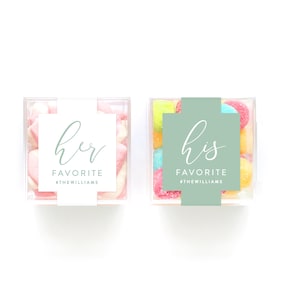May include: Two clear plastic containers filled with colorful candies. One container has a white label with the text "her favorite #thewilliams" and the other container has a green label with the text "his favorite #thewilliams".