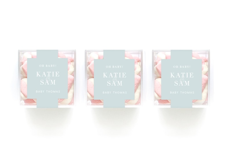 May include: Three clear boxes filled with pink and white marshmallows. Each box has a light blue label with the text "OH BABY! KATIE & SAM BABY THOMAS".