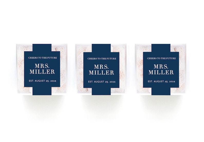May include: Three clear favor boxes filled with white candy. Each box has a blue label with the text "Cheers to the Future", "Mrs. Miller", and "Est. August 25, 2024".