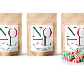 May include: Three brown kraft paper stand-up pouches with white labels featuring the text NOEL in large green and red letters, followed by MERRY CHRISTMAS THE MOORES. A pile of small, round, red and white striped peppermint candies sits in front.